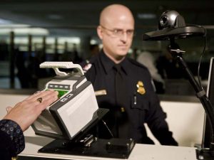 Department of Homeland Security(DHS) Officer Brian Pittack stands at his station with a new 10-fingerprint scanner(foreground) for international arriving passengers 10 December 2007 at Dulles International Airport in Dulles,Virginia. Foreigners who entered the United States at Dulles airport, near Washington, were required to give officials 10 fingerprints instead of two, as new security measures were rolled out Monday. "This is a more secure system that improves safety for everybody," Secretary of Homeland Security Michael Chertoff told a news conference at the airport. Most foreigners aged between 14 and 79 who travel to the United States have been required since 2004 to provide the prints of two fingers and a digital photograph to US officials, either when they apply for a visa or arrive in the United States. AFP PHOTO/PAUL J.RICHARDS (Photo credit should read PAUL J. RICHARDS/AFP/Getty Images)